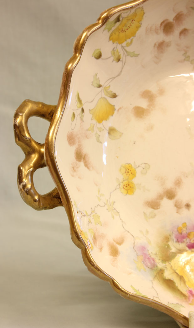 11402r6 Pretty Antique Pottery Shaped Bowl. Pretty Antique Pottery Shaped Bowl. This antique shaped bowl is decorated with flowers and leaves with gilt edge and handles. The sides of the bowl also having flower and leaf decoration. The base stamped with the registration number and a printed mark for WAA & Co England. Circa 1910